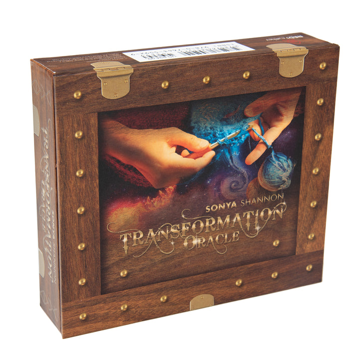 The Transformation Oracle by Schiffer Publishing, Ltd. comes in a wood-and-brass designed box featuring cover art of two hands weaving colorful threads on a cosmic background, symbolizing spiritual growth through oracle cards.