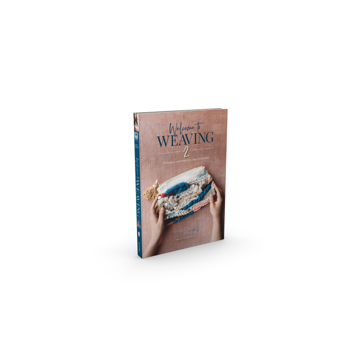 The book "Welcome to Weaving 2" by Schiffer Publishing, Ltd. features hands holding a woven textile on its pink cover and guides readers through intermediate weaving techniques and inspiring projects.