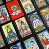 A vibrant spread of The Buddha Tarot by Schiffer Publishing, Ltd. showcases Eastern-inspired illustrations and symbolic figures on each card, including the Major Arcana, arranged neatly in rows.