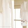 Embroidery Garden" by Schiffer Publishing, Ltd. is displayed before sunlit windows; a close-up highlights the delicate floral embroidery on the sleeve, showcasing the intricate texture and detail of this white shirt.