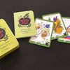 The Healthy Witch Oracle Cards by Schiffer Publishing, Ltd. are shown on a black surface with the box, guidebook, and three cards—Lemon, Squash, and Rainbow—each highlighting unique magick correspondences.