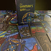 A box labeled The Shaman’s Way Oracle by Schiffer Publishing, Ltd. stands upright on illustrated oracle cards, all featuring intricate mystical symbols and vibrant spiritual artwork designed for spiritual healing.
