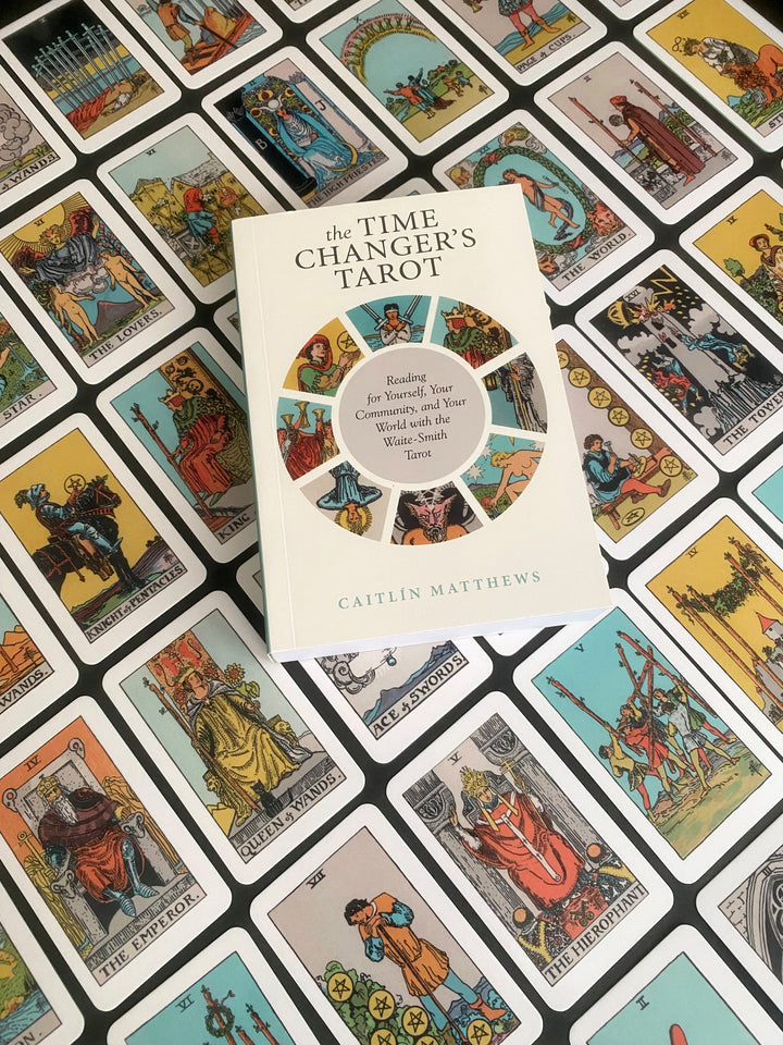 The Time Changer's Tarot by Schiffer Publishing, Ltd. rests on a spread of colorful cards from this modern tarot deck, each featuring vibrant reinterpretations of classic Waite-Smith Tarot archetypes.