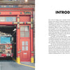 A fire truck numbered 74 is parked in a bright red garage marked ENGINE CO. 74, with open doors revealing the firehouse, equipment, and Paws of Firefighters by Schiffer Publishing, Ltd., celebrating cherished New York firefighter pets.
