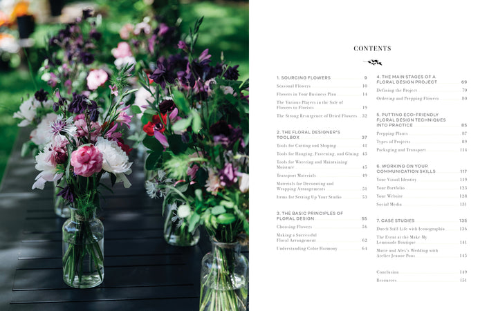 A row of glass jars with pink, purple, and white flowers sits on a dark outdoor table; next to them is "Starting Your Floral Design Studio" by Schiffer Publishing, Ltd., opened to the contents page on floral techniques and eco-friendly arranging.