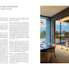 A modern office inspired by Penny Drue Baird features PowerHouse by Schiffer Publishing, Ltd., glass-enclosed wine storage, wooden shelves for bottles, a long desk with chairs, and a large window framing scenic mountain and tree views.