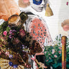 A surreal collage from Couture Tarot by Schiffer Publishing, Ltd. features a white-haired figure in a blue mask with gems, flowers, feathers, and gold, evoking couture tarot elegance. “Page of Swords” appears at the bottom from this fashion tarot deck.