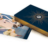 The Couture Tarot by Schiffer Publishing, Ltd. features gold-edged cards and a striking gold sunburst back. One card showcases illustrated flamingos with floral accents on a pastel background, enhancing its elegant appeal.