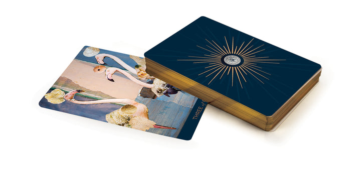 The Couture Tarot by Schiffer Publishing, Ltd. features gold-edged cards and a striking gold sunburst back. One card showcases illustrated flamingos with floral accents on a pastel background, enhancing its elegant appeal.