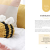 A chunky yarn, yellow and black bumblebee toy with white wings rests on a textured pink and white blanket, surrounded by pillows. On the right are text instructions and supplies from "Get Started in Finger Knitting" by Schiffer Publishing, Ltd.
