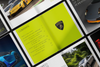 An open Automobili Lamborghini Special Edition book by Schiffer Publishing, Ltd. features a vivid yellow-green contents page with the badge and pages highlighting luxury sportscars alongside engaging text.