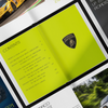 An open Automobili Lamborghini Special Edition book by Schiffer Publishing, Ltd. features a vivid yellow-green contents page with the badge and pages highlighting luxury sportscars alongside engaging text.