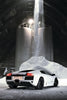 An Automobili Lamborghini Special Edition by Schiffer Publishing, Ltd. is parked inside a spacious industrial building with white powder beneath silos and a stream of material falling from above.