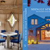 Front cover of *Shingle Style Houses* by Schiffer Publishing, Ltd. shows a blue shingle style home at dusk; back cover features a cozy dining nook with table, chairs, and star-shaped window—capturing the warmth of shingle style architecture.
