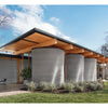 Showcasing ideas from "10 Innovations That Will Shape Tomorrow's Architecture" by Schiffer Publishing, Ltd., a modern building with curved concrete walls and a flat roof stands amid greenery, with outdoor furniture arranged on gravel nearby.