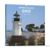 Front cover of Shores & Islands Ohio by Schiffer Publishing, Ltd., showing a white lighthouse, sandy beach, green lawns, and houses near Lake Erie’s renowned vacation spots under a clear sky.