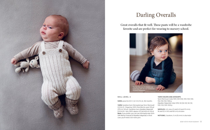A baby in Nordic-inspired knitwear from "Baby Knits from Norway" by Schiffer Publishing, Ltd. lies on a soft gray surface with a stuffed bunny, while a toddler in dark overalls and sweater sits nearby, looking off to the side.