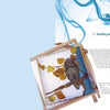 A wooden frame displays silk painted with an owl and yellow leaves, blue smoke-like designs above. On the right, "The Fine Art of Painting on Silk" by Schiffer Publishing, Ltd. is titled with a helpful instructional paragraph below.