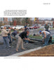 Construction workers pave a roadway with pervious concrete, as described in "Paving with Pervious Concrete" by Schiffer Publishing, Ltd., with buildings, vehicles, and trees visible in the background.