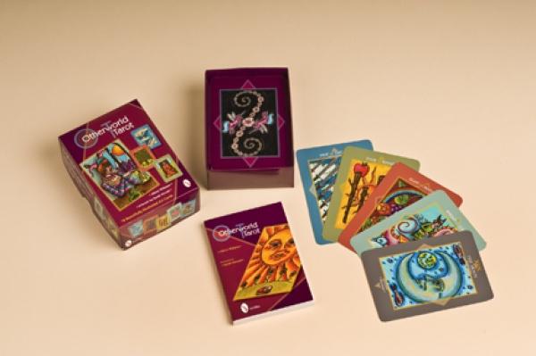 The Otherworld Tarot deck, displayed on a beige surface, includes an open box, a Tarot reading guide booklet, and several vividly illustrated cards artfully spread out.