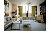 Modern living room inspired by Showhouses 2 from Schiffer Publishing, Ltd., featuring a beige sofa, two ottomans, glass coffee table, abstract painting, tall white vases, armchair, geometric chandelier, and green curtains.