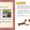 Two pages from "Meet Me in My Cape Cod Kitchen" by Schiffer Publishing, Ltd.: the left shares a baking story with a photo of stacked cookies; the right features a “Surprise Cookies” recipe and animal-shaped seaside treats.