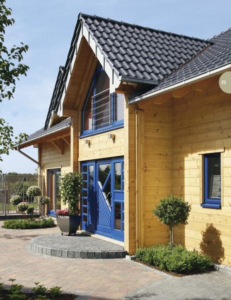 The Contemporary Log Home by Schiffer Publishing, Ltd. showcases a modern wooden house with light yellow timber walls, blue window frames and doors, a dark tiled roof, potted plants, and a brick path—an ideal sustainable building.