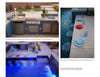 Inspired by *New Ideas for Living Outdoors* by Schiffer Publishing, Ltd., this sleek outdoor kitchen with grill, sink, and storage beside a glowing pool features blue mosaic tiles and chic tableware for ultimate backyard style and relaxation.