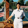 A person in a white captain’s uniform stands by a ship’s wheel with an American flag, evoking Chesapeake Bay’s spirit—just like "Chesapeake Women" from Schiffer Publishing, Ltd. celebrates the region and its storytellers.