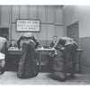 In "Grunts" by Schiffer Publishing, Ltd., four soldiers with duffel bags stand at a table while two men sit behind it, echoing classic U.S. Army draft scenes in photojournalistic essay style.
