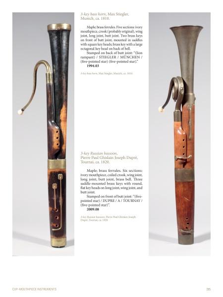 Shown upright in both side and front views, two rare 19th-century wooden bass horns with brass fittings are featured in "Four Centuries of Musical Instruments" by Schiffer Publishing, Ltd., highlighting their unique keys and worn, patched areas.