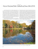 A scenic pond in Grover Cleveland Park, featured in "Olmsted Parks in New Jersey" by Schiffer Publishing, Ltd., reflects autumn colors. A path and benches border the water as people stroll under a clear blue sky.