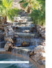 Swimming Pool Innovations by Schiffer Publishing, Ltd. features cascading waterfalls over stone steps, rocks, and palms, ending in a clear pool, with sunlight filtering through fronds—perfect inspiration for your backyard swimming pool paradise.