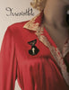 A mannequin displays vintage-inspired elegance in a red dress with a beige lace collar and black cat brooch. “Irresistible: The Art of Lingerie, 1920s-1980s” by Schiffer Publishing, Ltd. appears in cursive at the top left.