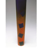 “Turning to Art in Wood” by Schiffer Publishing, Ltd. is a tall, cylindrical sculpture featuring a purple-to-orange gradient and four evenly spaced dark blue squares in a vertical line, shown upright against a plain white background.