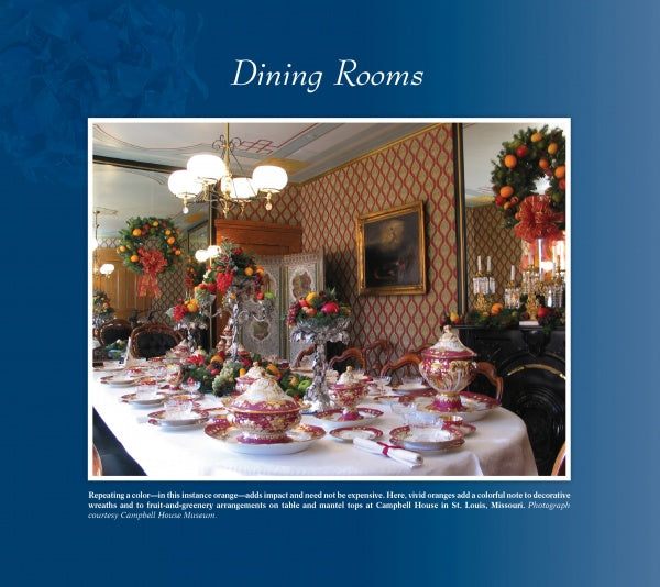 A formal dining room adorned with festive décor inspired by "Delicious Christmas Decorations at Historic Houses and Your Home" by Schiffer Publishing, Ltd., featuring dried fruit wreaths, ornate tableware, patterned wallpaper, and elegant mirrors.