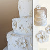 The Art of the Wedding Cake by Schiffer Publishing, Ltd. features a three-tiered white fondant cake with elegant white florals, small blossoms, and silver beads—ideal for wedding cake guides or decoration inspiration.