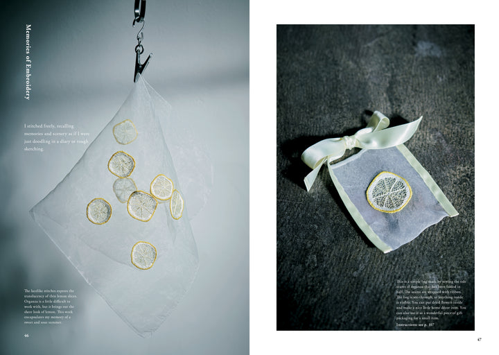 Juno's Nature Embroidery Notebook by Schiffer Publishing, Ltd. features delicate lemon slice and botanical embroidery designs, displayed on white mesh pouches—one hanging from a hook, another tied with ribbon on a dark surface.