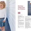 A smiling, curly-haired child models a white long-sleeve top and blue knitted skirt from "All-Year-Round Knitting for Little Sweethearts" by Schiffer Publishing, Ltd., shown on a wooden deck with highlighted KlompeLompe patterns.